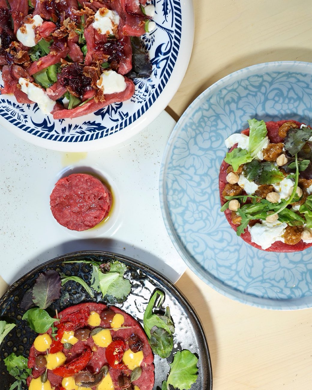 Quattro piatti di carpaccio e tartare fotografati dall'alto da Miketing per un ristorante